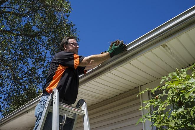 smiling worker fixing gutters on a residential home in Andale KS